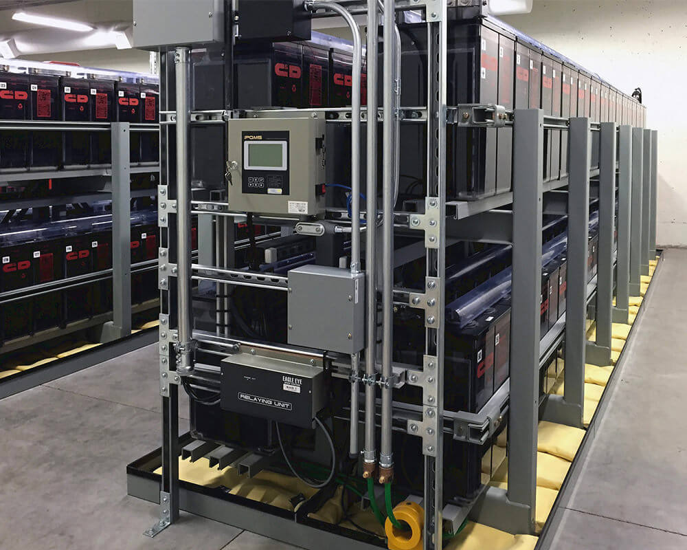 Eagle Eye Power Solutions iPQMS battery monitoring system mounted to wall of batteries in large battery room