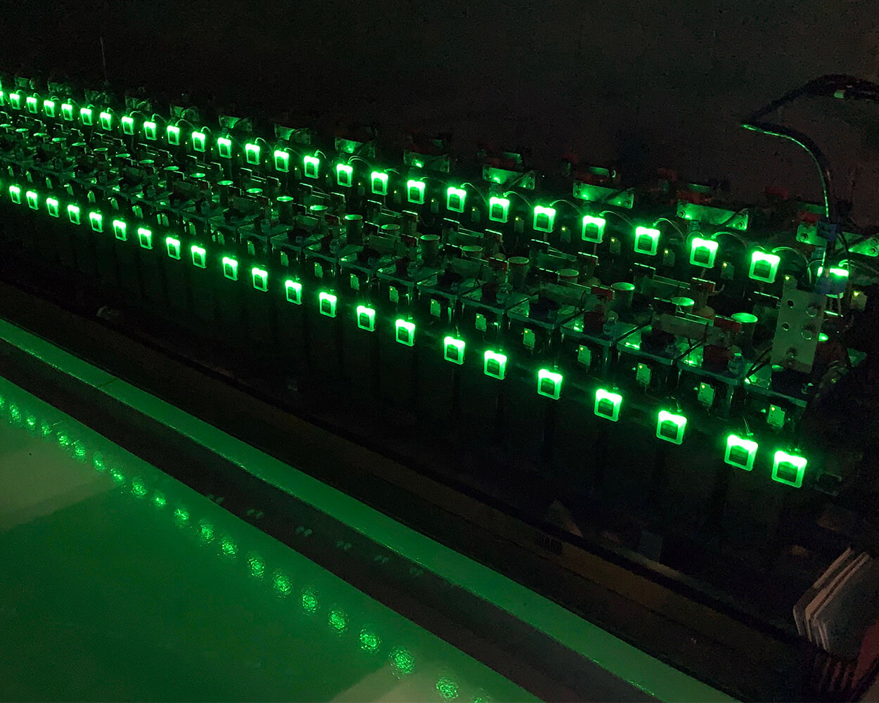 Rows of batteries in the dark with glowing green Eagle Eye Power Solutions Vigilant battery monitoring sensors