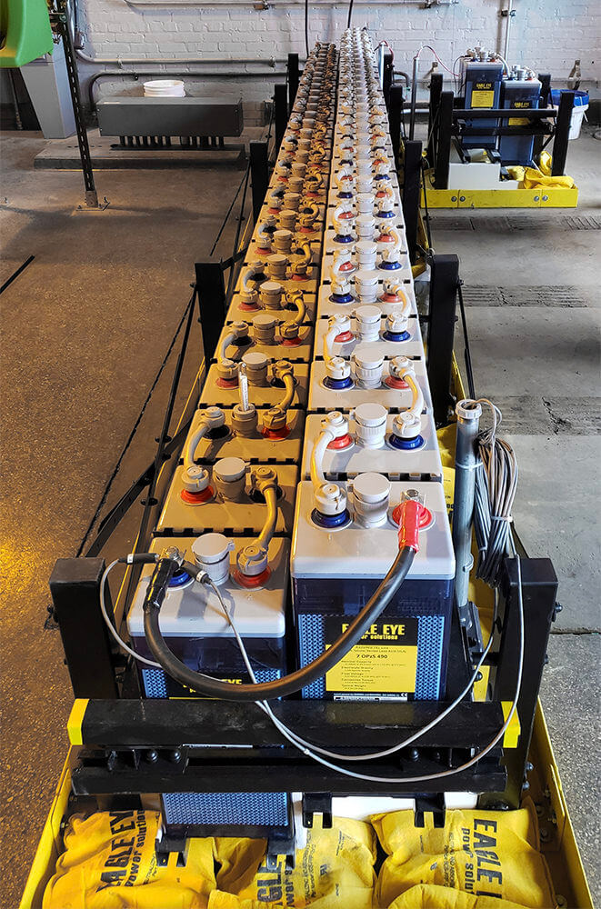 Two long rows of Eagle Eye Power Solutions flooded lead acid batteries with spill containment