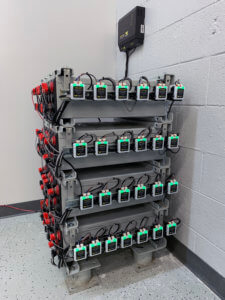 4 short rows of batteries with Eagle Eye Power Solutions Vigilant battery monitor sensors facing, green sensor lights all lits