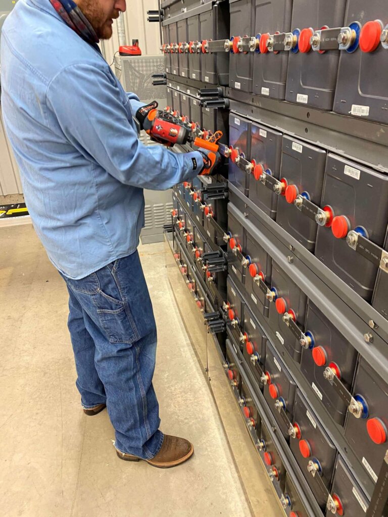 Eagle Eye Services technician finalizing a battery installation on a row of batteries.