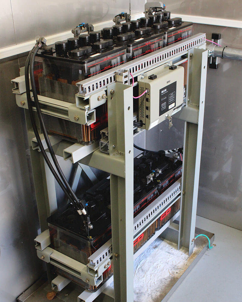 Two small racks of batteries inside storage unit with Eagle Eye Power Solutions BDS-Pro battery monitor