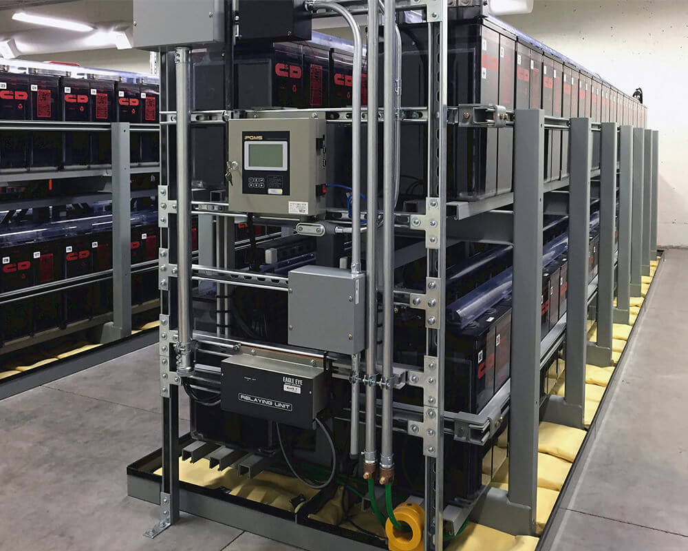 Eagle Eye Power Solutions iPQMS battery monitoring system mounted to wall of batteries in large battery room