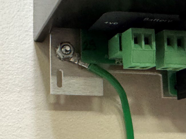 Close-up image showing a properly grounded Eagle Eye Power Solutions Vigilant® battery monitor. A green 14AWG stranded ground wire is securely crimped and fastened to the monitor's grounding lug, routed behind the power and sense input plugs as required.