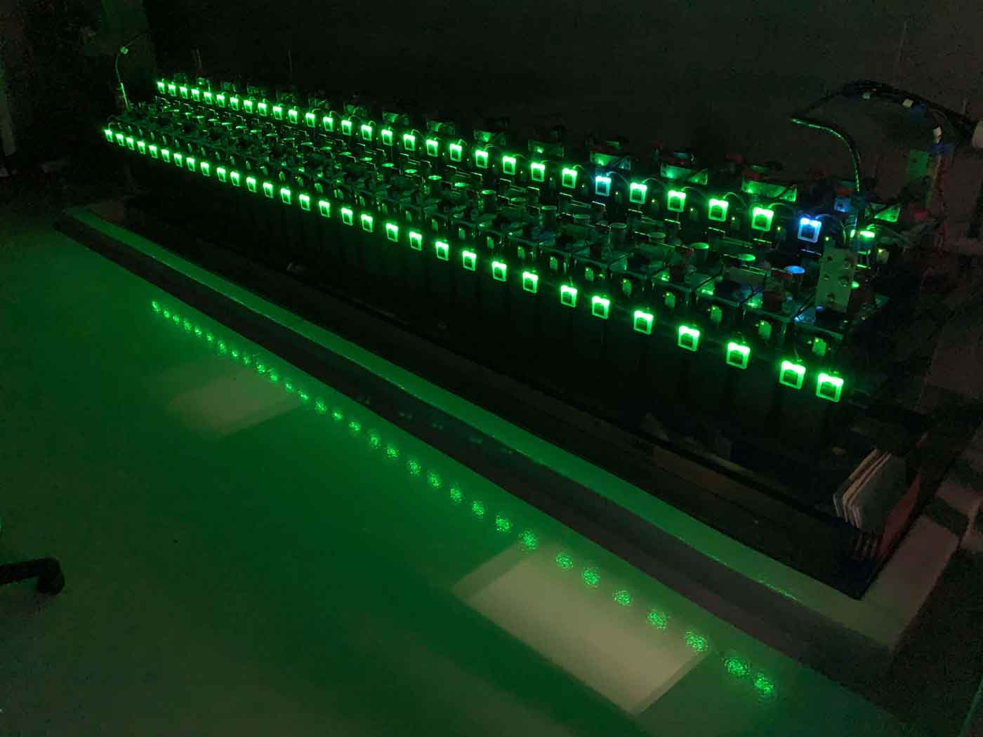 Eagle Eye Power Solutions Vigilant Battery Monitoring System attached to two rows of stationary batteries, with ELM Sensors glowing green, in a dark battery room.