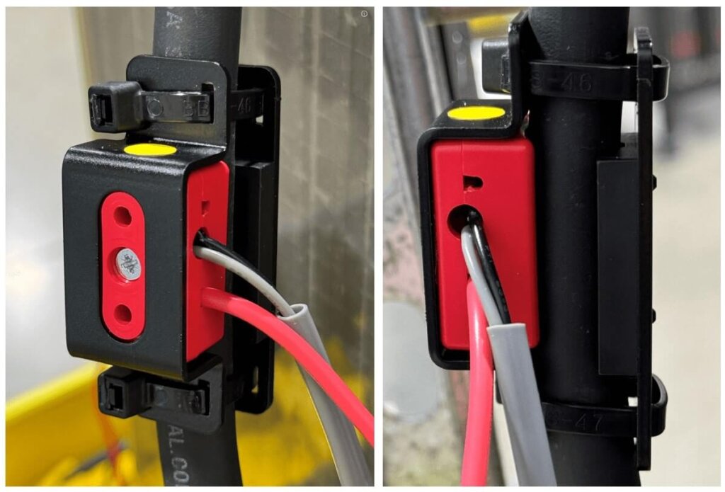 Two close-up views of a sensor clamped onto a battery cable using a black bracket and yellow dot alignment marker. Red and gray wires are routed through the sensor, and zip ties secure the clamp tightly around the cable. The left image shows the grub screw properly tightened with the cable tie head flush against the bracket. The right image shows an alternate angle, emphasizing the correct installation despite slight visual misalignment of the clamp.