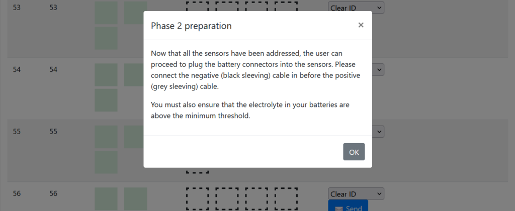 Screenshot of a pop-up message on the Vigilant® monitor interface indicating the system is ready for Phase 2. The message instructs the user to connect the battery cables to the sensors, ensuring the negative (black sleeving) cable is connected before the positive (grey sleeving) cable, and to verify that the battery electrolyte level is above the minimum threshold.
