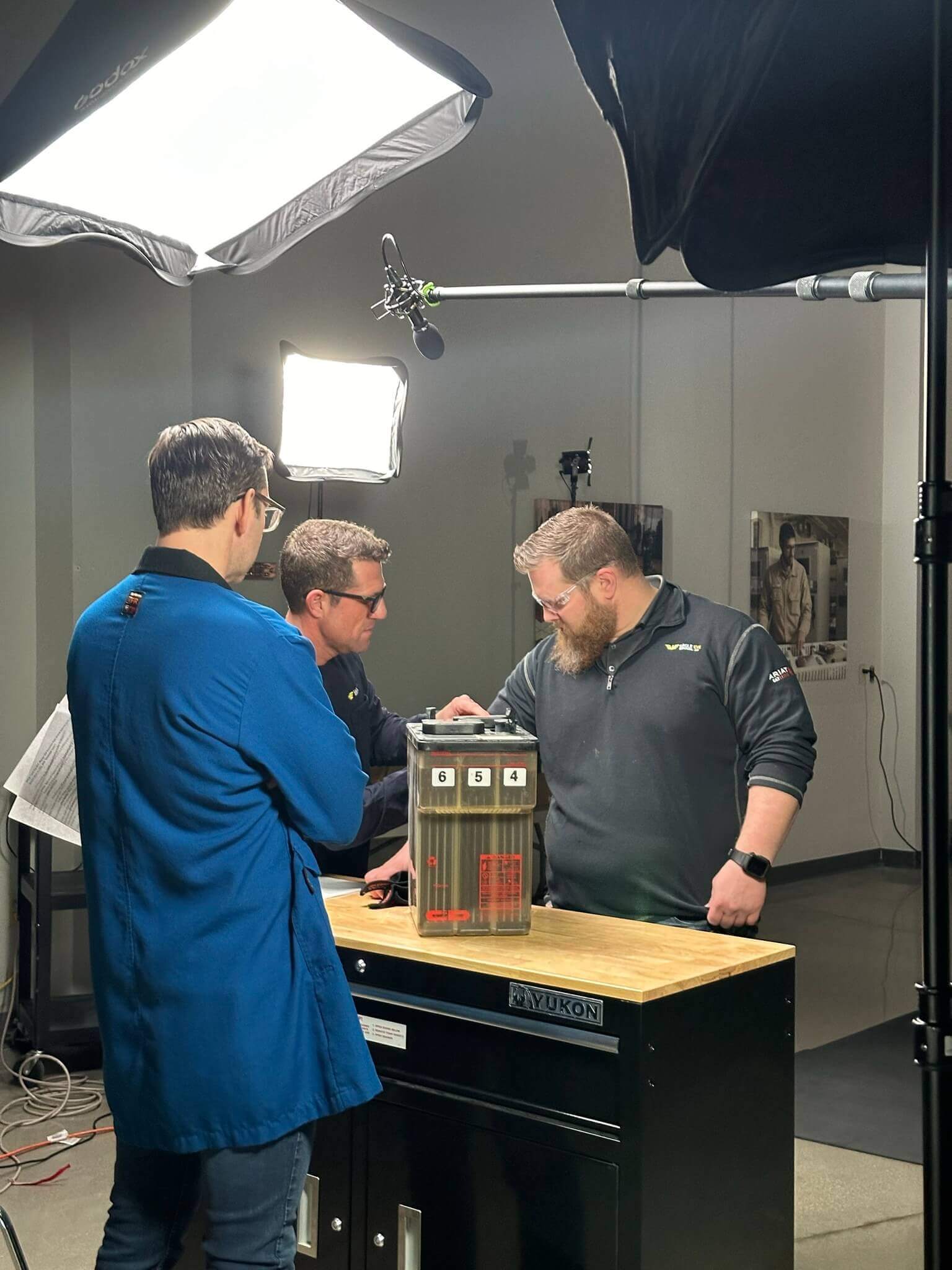 Three team members collaborating on a battery testing demonstration under professional studio lighting, showcasing Eagle Eye Power Solutions' expertise and commitment to innovation.