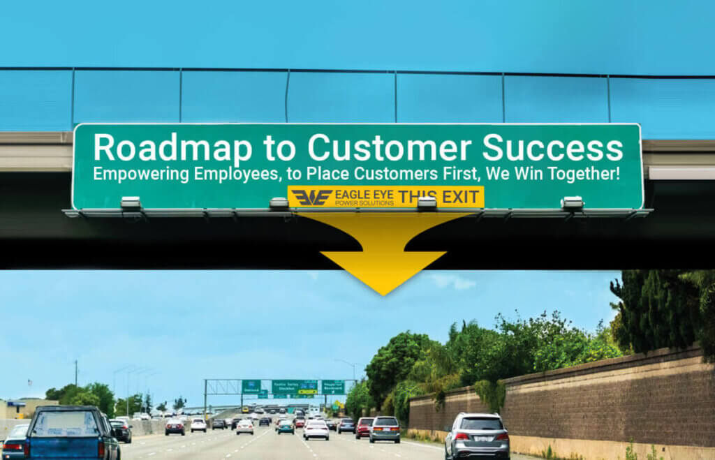 A digitally edited highway road sign reads "Roadmap to Customer Success – Empowering Employees, to Place Customers First, We Win Together!" with a large yellow arrow pointing down and the Eagle Eye Power Solutions logo and text “This Exit” displayed below the sign, symbolizing a strategic path toward customer success.