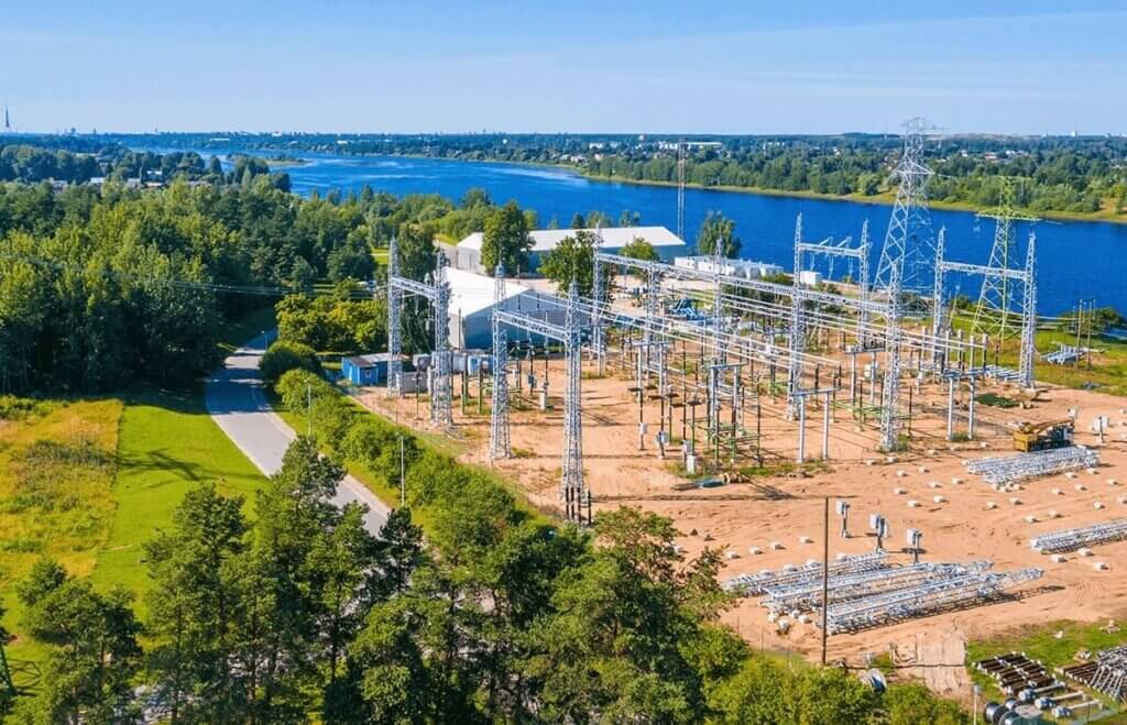 Aerial view of Alliant Energy substation in Wisconsin, showing power lines and equipment near a river, surrounded by trees and buildings.