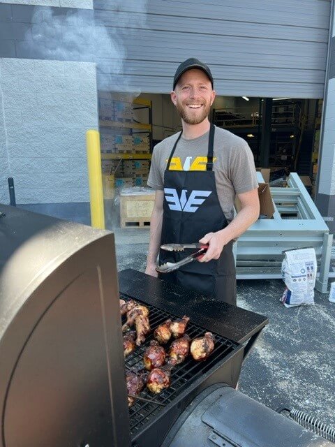 Kory Hooper, Technical Product Manager at Eagle Eye Power Solutions, grilling chicken during a company cookout outside the facility.