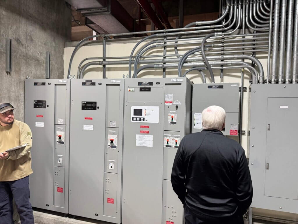 Eagle Eye University instructor George Pedersen inspecting Homer Electric Association’s DC power system, checking wiring and instrumentation to locate a charger-detected ground fault.