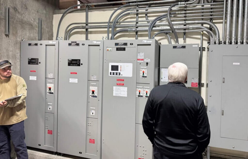 Eagle Eye University instructor George Pedersen inspecting Homer Electric Association’s DC power system, checking wiring and instrumentation to locate a charger-detected ground fault.